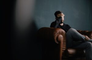 A man sitting on a sofa suffering from a headache