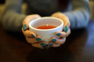 A woman's hands holding a cup of Sakae Naa