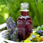 A bottle of vinegar tincture surrounded by flowers