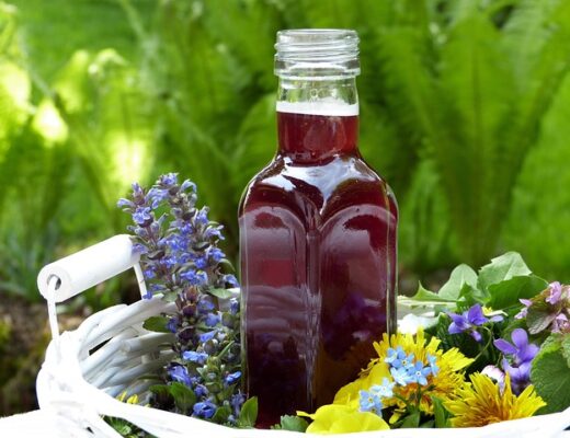 A bottle of vinegar tincture surrounded by flowers
