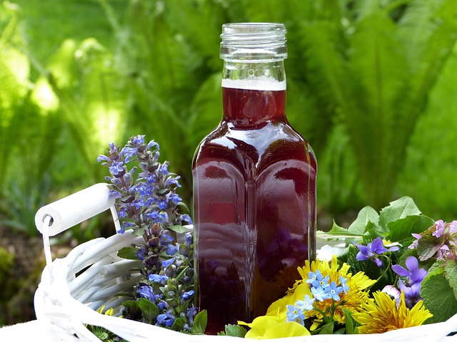 A bottle of vinegar tincture surrounded by flowers